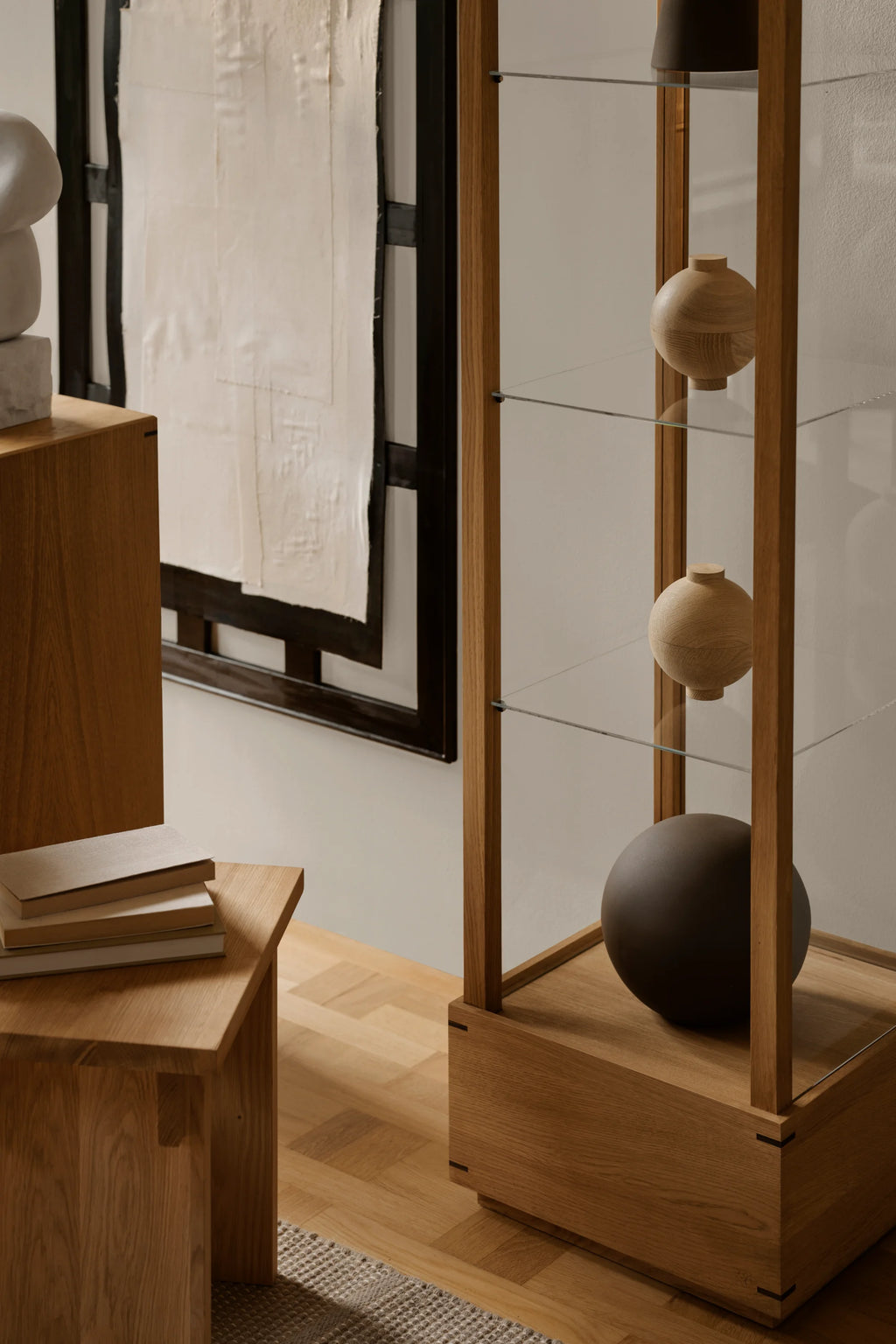 Kristina Dam Japanese Cabinet M, a minimalist display cabinet crafted from warm natural solid oak wood with clean lines and clear glass shelves, embodying a modern Japanese design aesthetic. This elegant showcase cabinet is ideal for stylishly presenting collectibles or decor in a contemporary living room, dining room, or sophisticated office space.