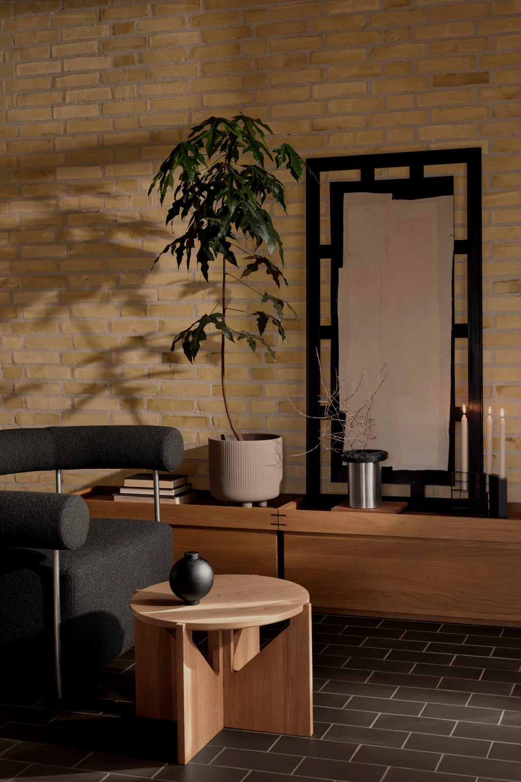 Kristina Dam Simple Coffee Table, a modern minimalist round coffee table crafted from solid natural oak wood. It features a clean circular tabletop supported by a unique geometric base with three interlocking wooden panels, showcasing a light wood grain finish. This Scandinavian-inspired oak coffee table is perfect for contemporary living rooms, cozy reading nooks, or as a stylish accent table.