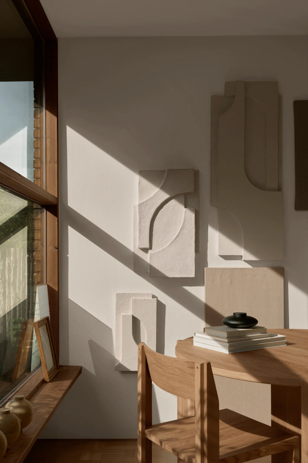 Kristina Dam Serif Relief S, a modern minimalist sculptural wall art piece featuring a raised geometric relief design with soft curves and straight lines, crafted from textured off-white plaster. This contemporary abstract wall decor adds organic modern elegance to living rooms, bedrooms, or gallery walls.