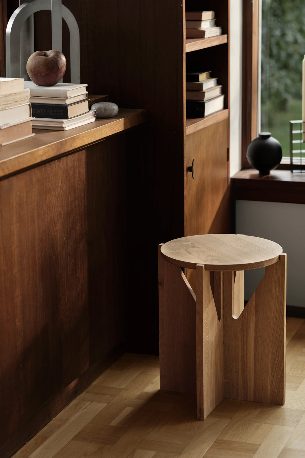 Kristina Dam Simple Stool, a modern minimalist stool crafted from natural solid oak wood, featuring a round top and three interlocking flat legs with geometric cut-out details, showcasing the light wood grain and Scandinavian design aesthetic. This versatile designer wood stool is perfect as a contemporary side table for living rooms, a bedside table, or an entryway accent.