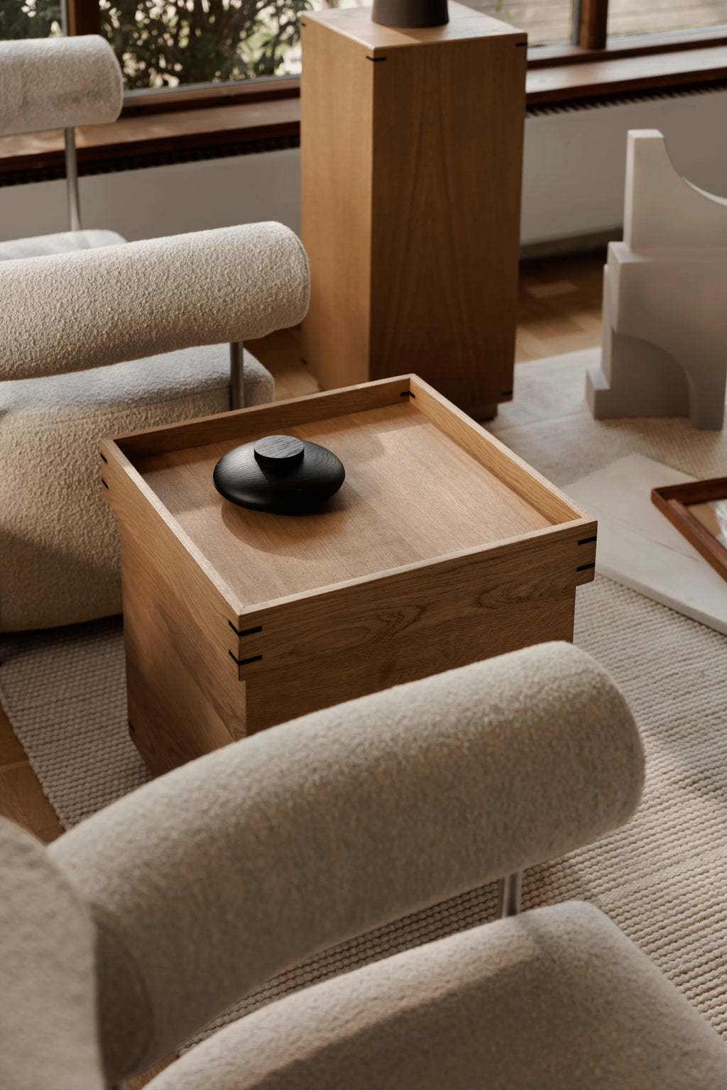 Kristina Dam Japanese Tray Table, a modern minimalist square coffee table crafted from solid light oak wood with a distinctive recessed tray top and elegant black-stained joinery details. Its clean lines and natural wood grain embody a Japandi aesthetic, creating a sophisticated accent piece. Perfect as a stylish side table or coffee table for Scandinavian living rooms and contemporary lounge spaces.