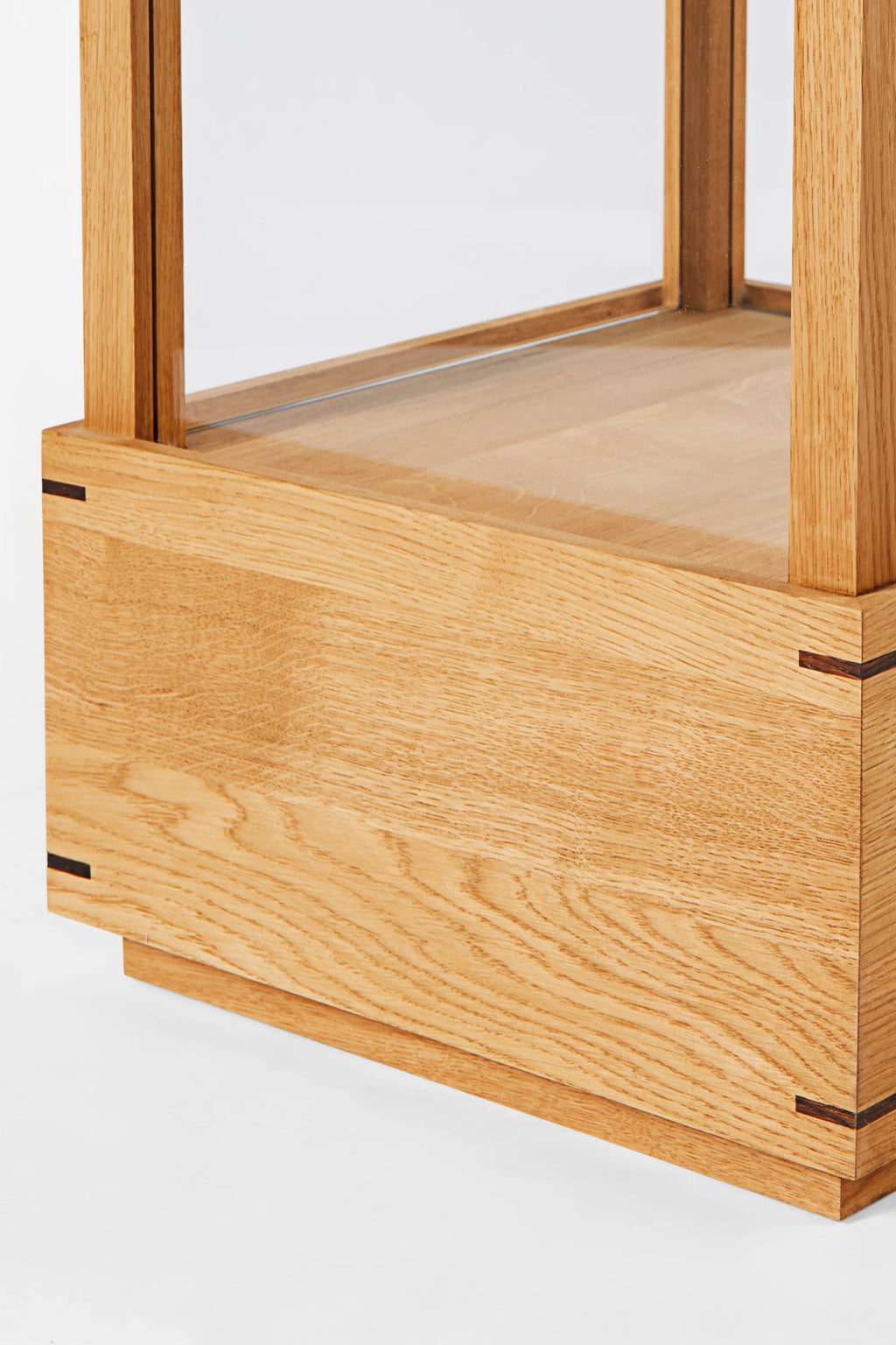 Kristina Dam Japanese Cabinet M, a minimalist solid oak display cabinet featuring natural light oak wood with prominent grain, clear glass panels, and striking dark wood splines at the corners, showcasing precise Japanese-inspired joinery. This modern Scandinavian storage cabinet is perfect for elegant living room display or contemporary dining room organization.