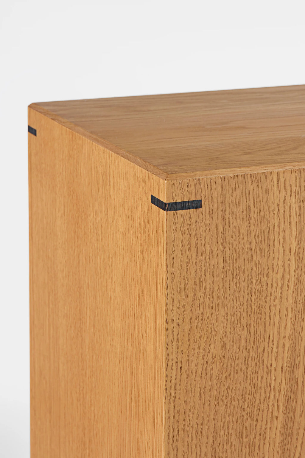 Kristina Dam Japanese Pedestal, a modern minimalist solid oak wood pedestal featuring a natural light oak finish with striking black key joint details at each corner, creating a clean geometric block silhouette. This Scandinavian-inspired oak plinth is ideal for displaying art or plants in a contemporary living room, entryway, or bedroom accent.