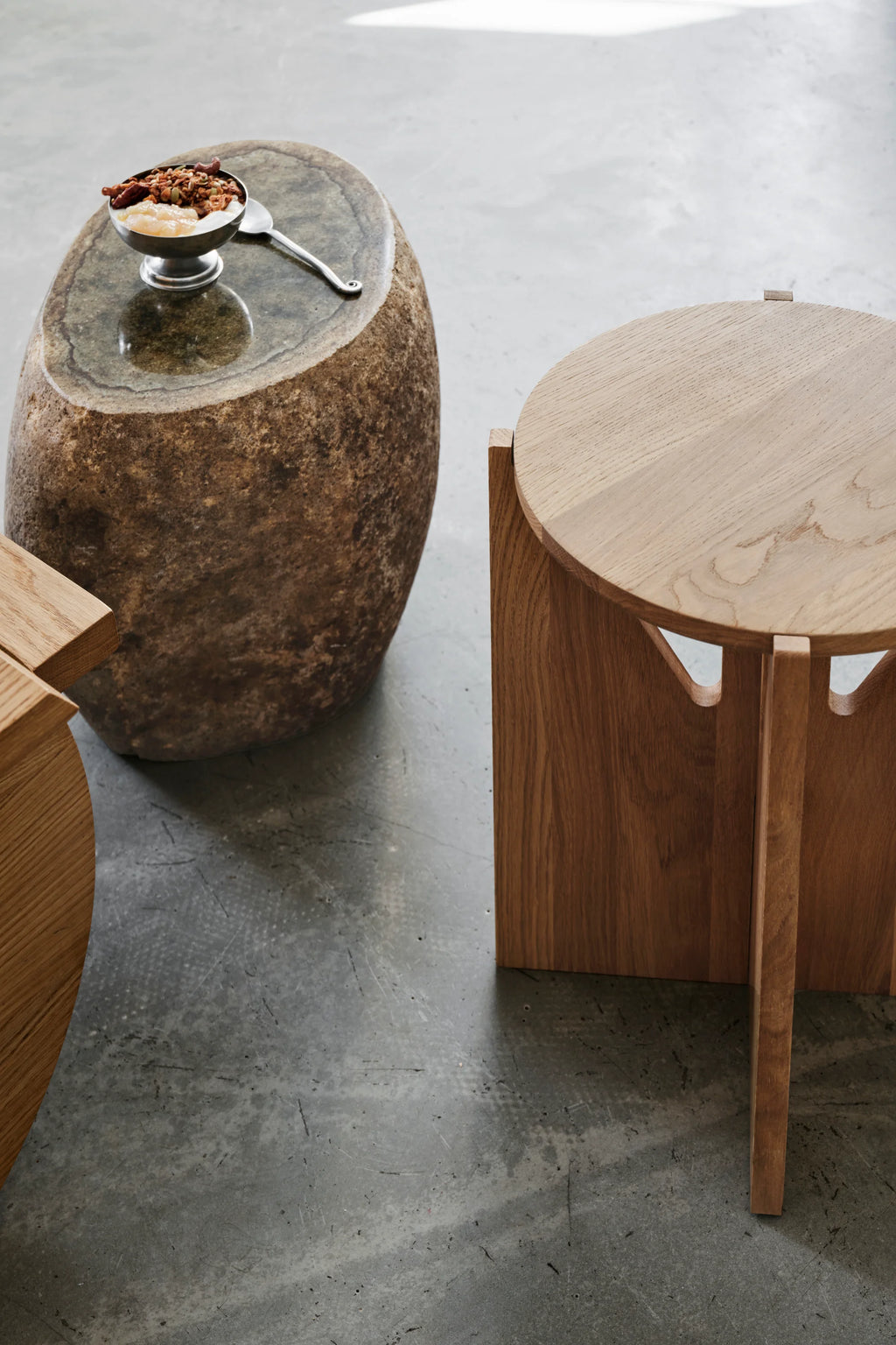 Kristina Dam Simple Stool, a minimalist Scandinavian solid oak stool featuring a smooth round top and a distinctive geometric base with architectural cut-outs, highlighting the beautiful natural wood grain. This contemporary oak accent stool or side table is ideal for modern minimalist living rooms, cozy reading nooks, or as a bedside table in Nordic-inspired bedrooms.