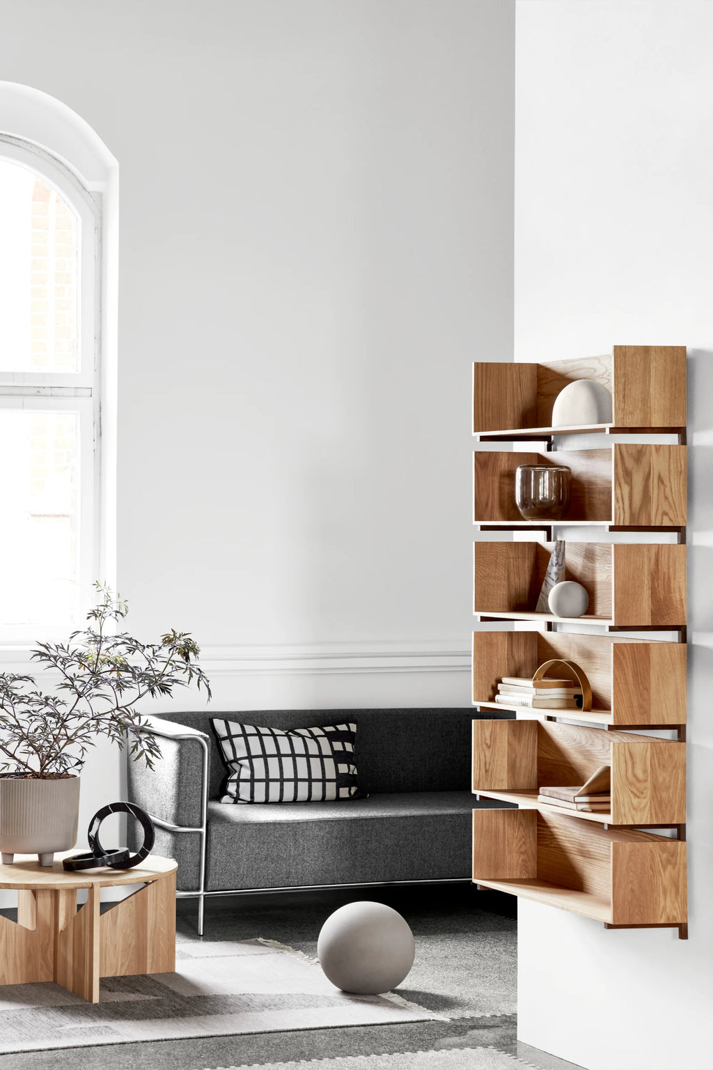 Kristina Dam Simple XL Coffee Table, a round modern minimalist coffee table crafted from light natural solid oak wood, featuring a smooth tabletop and a distinctive geometric base with intersecting vertical panels. This Scandinavian-inspired oak coffee table is perfect for contemporary living rooms, cozy reading nooks, or as a stylish side table.