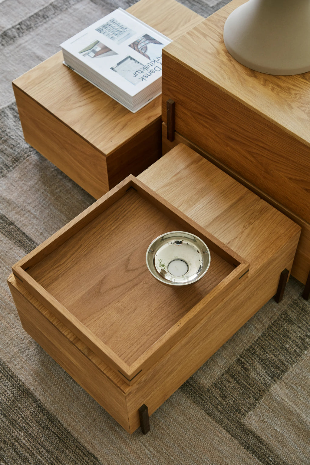 Kristina Dam Stack Storage Box, a modern minimalist modular storage system crafted from natural solid oak wood with clean lines and subtle dark brown corner accents. This versatile Scandinavian design features stackable rectangular boxes, one with a recessed tray top, perfect for a contemporary living room as a side table, coffee table, or elegant display unit.