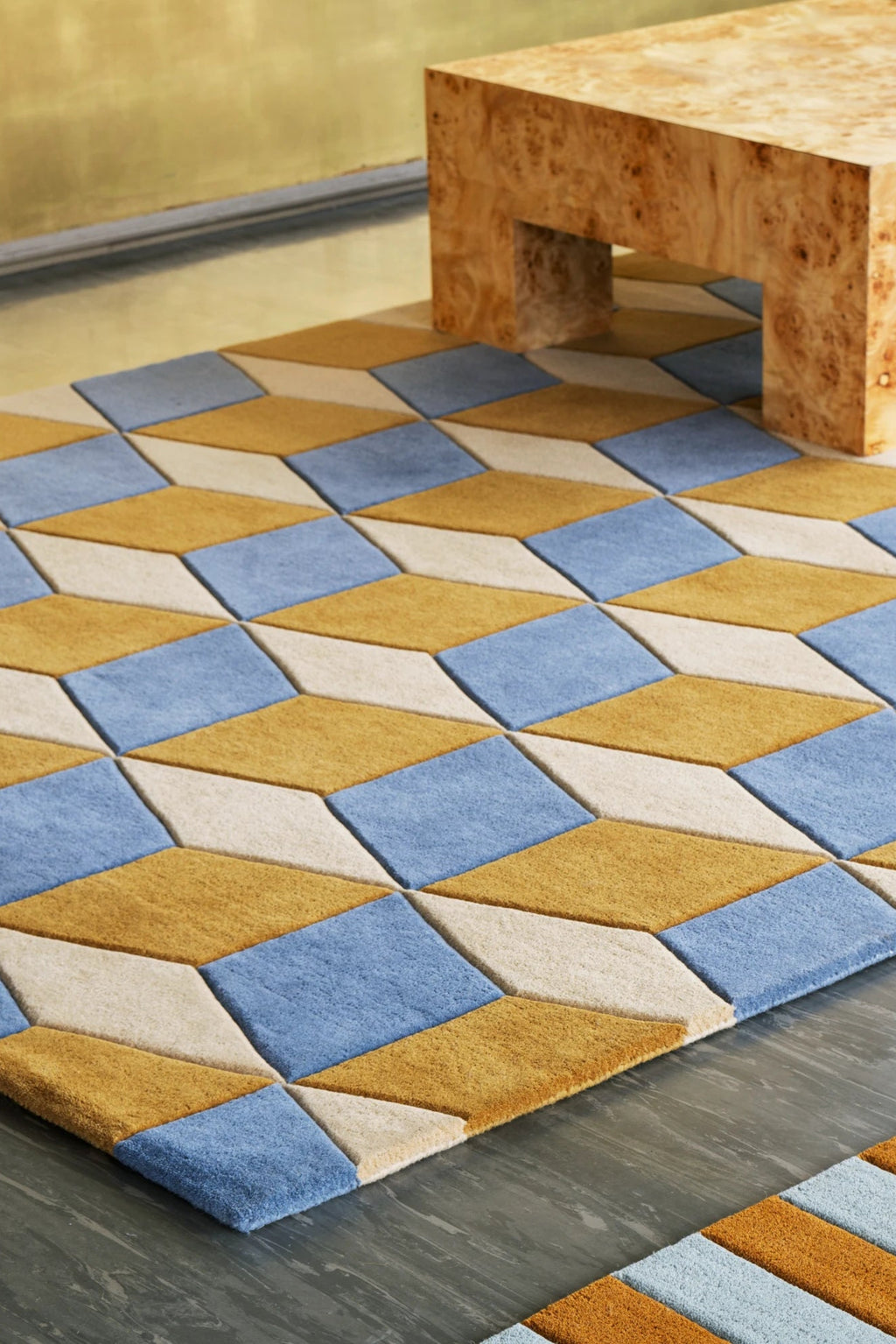 Layered Illusion Wool Rug, a geometric patterned area rug featuring an optical illusion design with diamond shapes in blue, gold, and cream colors. Perfect for adding a modern, playful touch to liv...