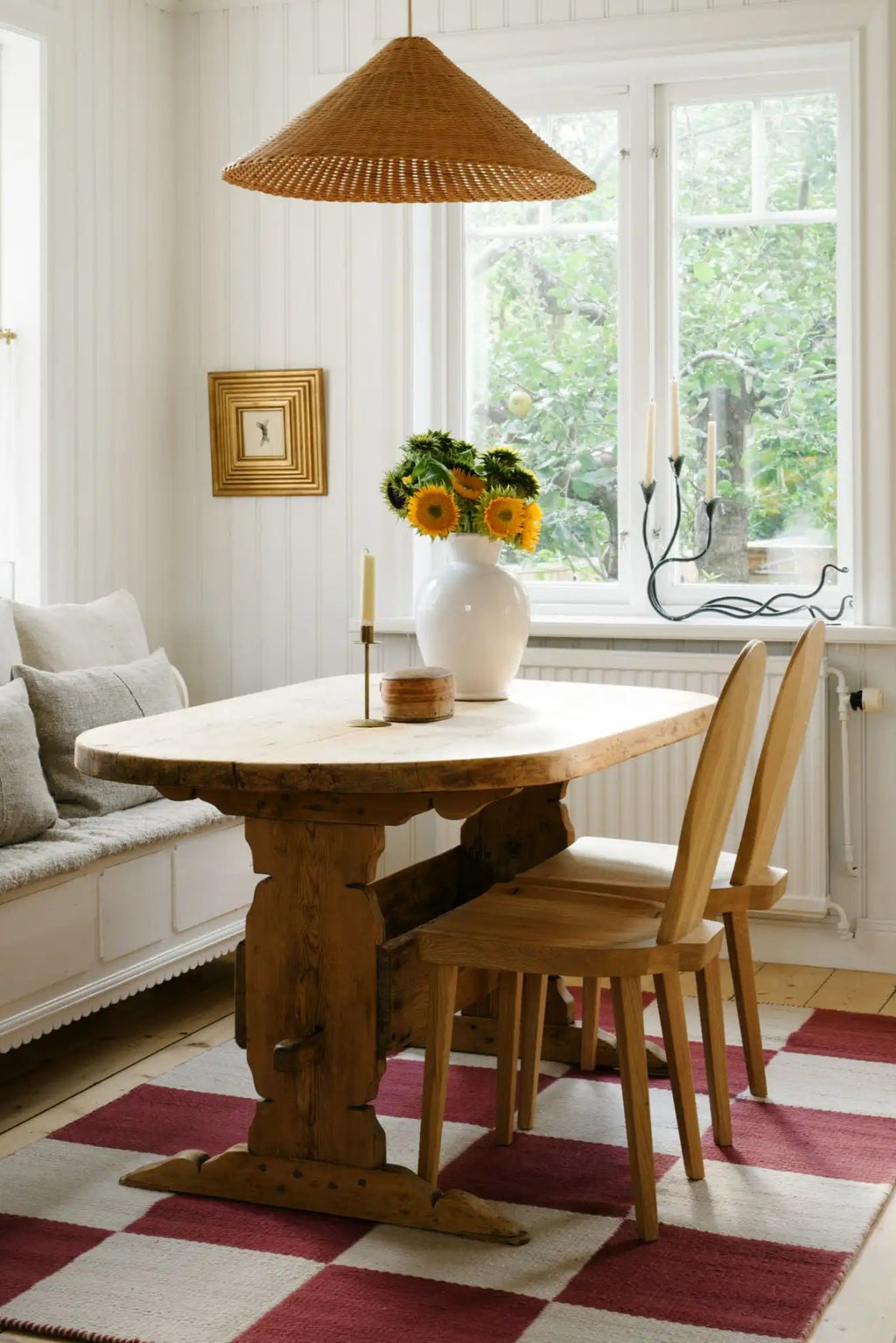 Layered Chess Wool Rug, an eye-catching woven area rug featuring a large red and white checkerboard pattern, placed under a rustic wooden dining table. Perfect for adding a bold, traditional accent...
