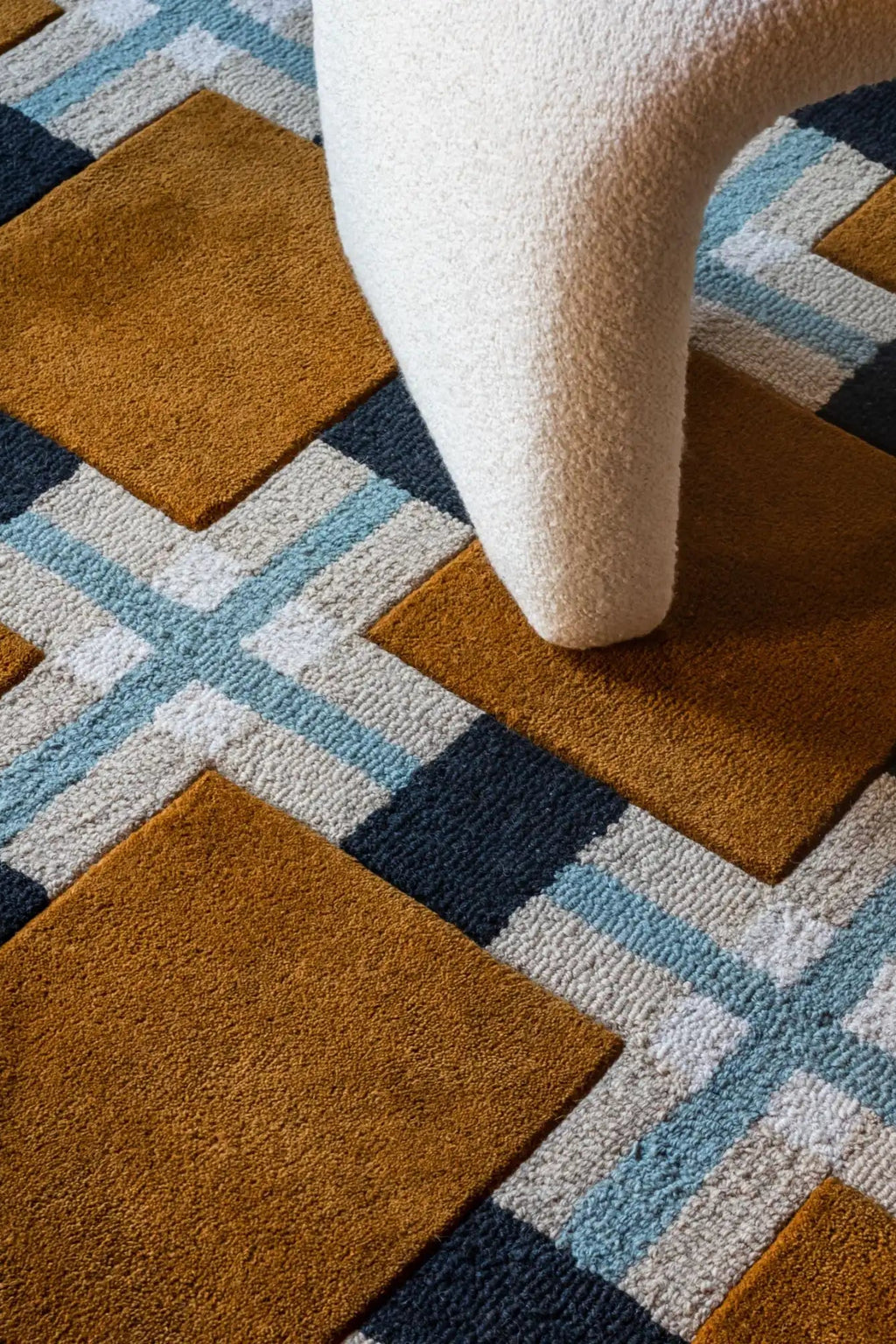 Layered Ochre Fields Wool Rug, a modern geometric pattern rug featuring blocks of ochre, dark blue, light blue, and grey/white wool. Perfect for adding a contemporary, colorful touch to any living...