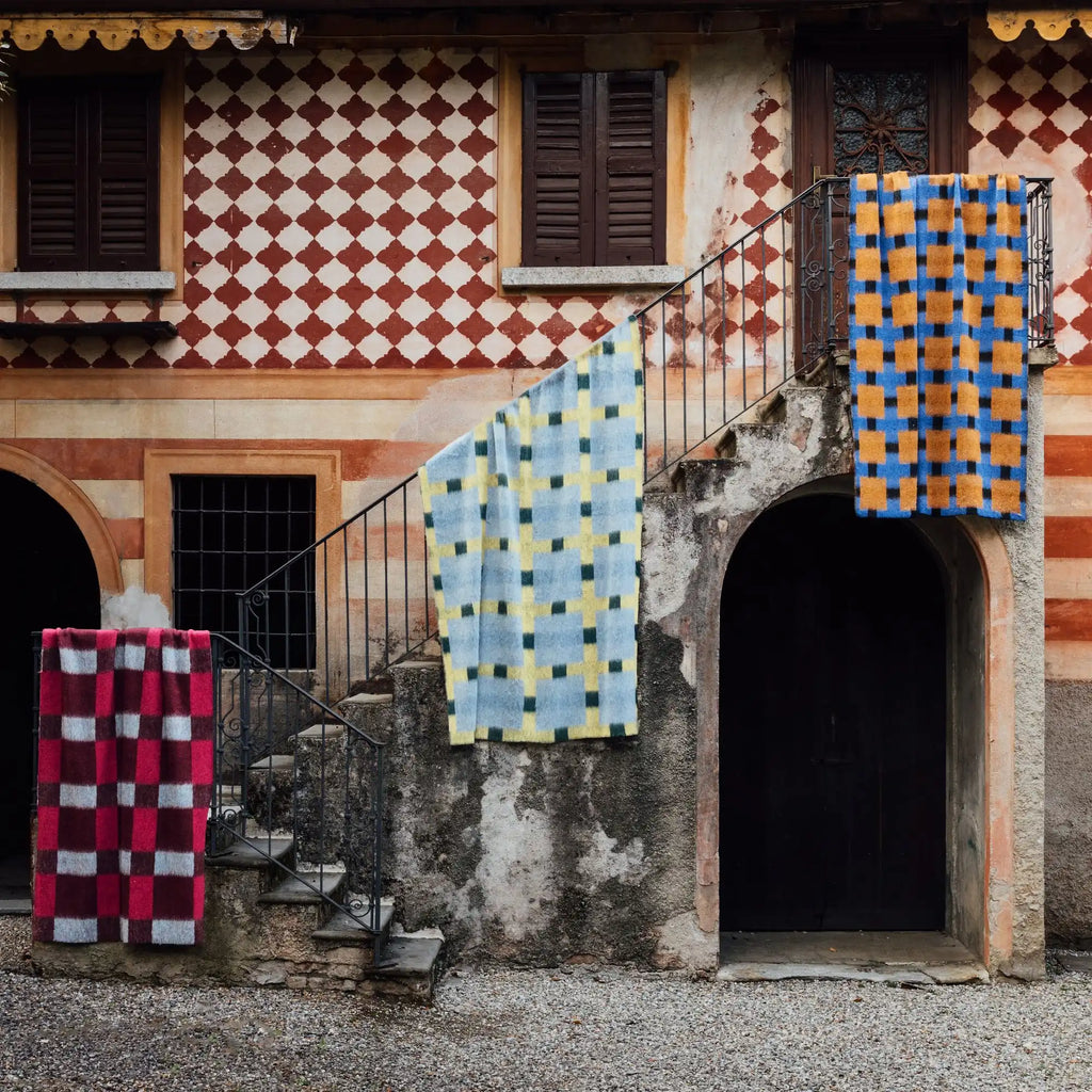Layered Fall Foliage Oversized Blanket, a collection of three plush throws with bold checkered patterns in blue/orange, light blue/yellow/green, and red/burgundy/grey. Perfect for adding warmth and...