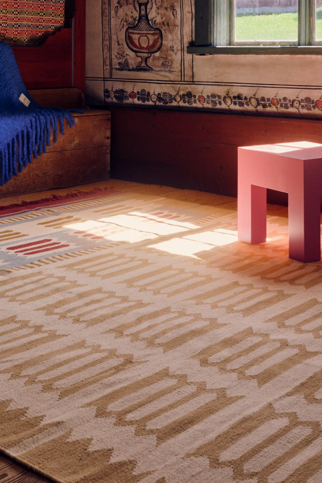 Layered Hilma Wool Rug, a light beige and brown woven wool rug with a geometric pattern and red accents, featuring a flatweave design. Perfect for adding warmth and texture to any living room or be...