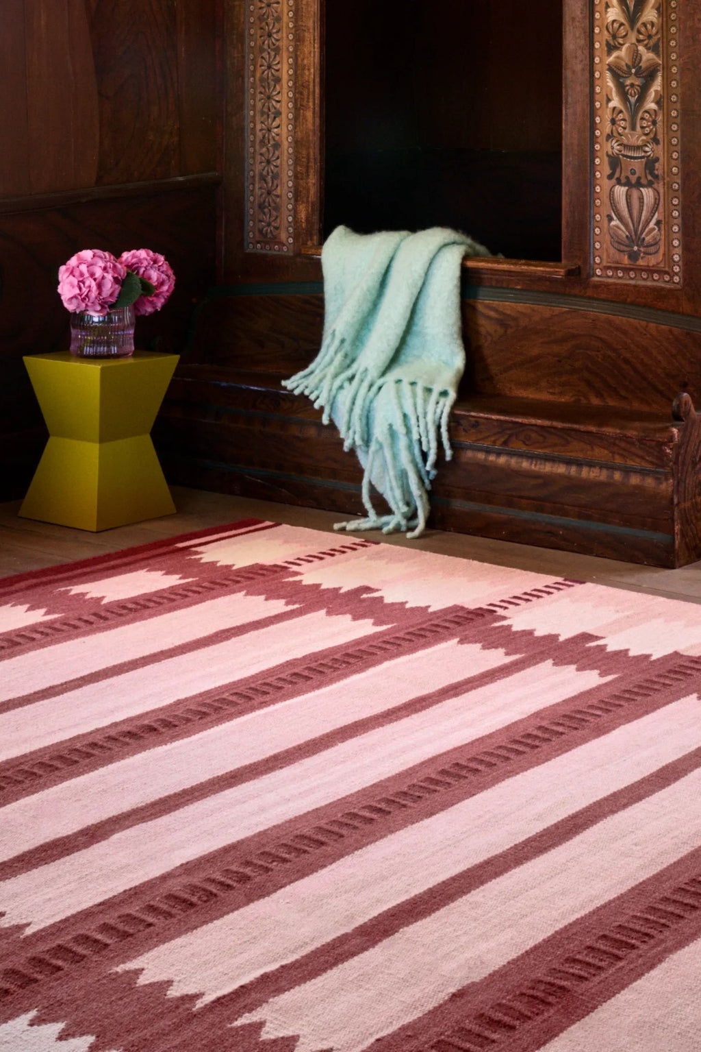 Layered Iris Wool Rug - Raspberry, a vibrant raspberry pink and light pink striped wool rug with a subtle geometric pattern. Perfect for adding warmth and a modern touch to any living room or bedro...