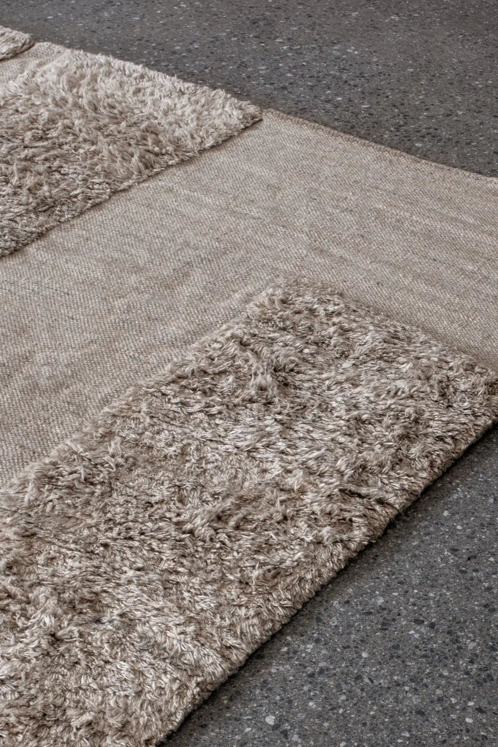 Layered Punja Bricks Wool Rug, a luxurious light beige wool rug with a textured brick pattern featuring both flat-woven and high-pile shag sections. Perfect for adding warmth and sophisticated styl...