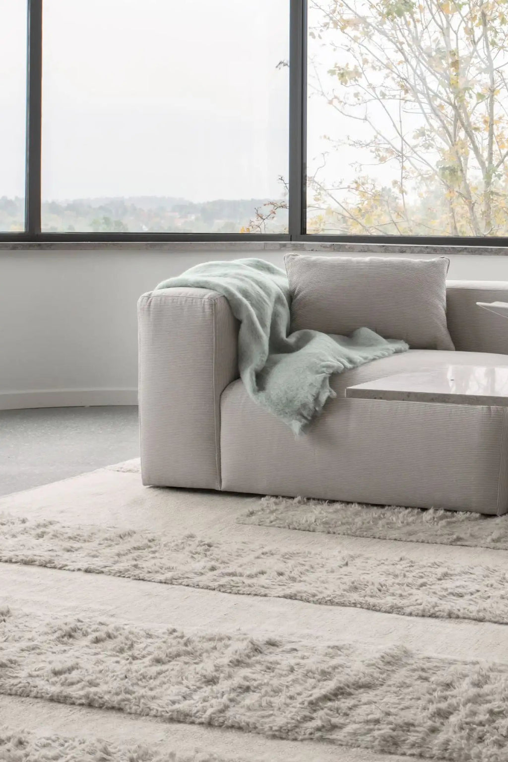 Layered Punja Bricks Wool Rug, a textured off-white area rug with alternating flat and shaggy stripe patterns, made from soft, natural wool. Perfect for adding warmth and sophisticated style to a m...