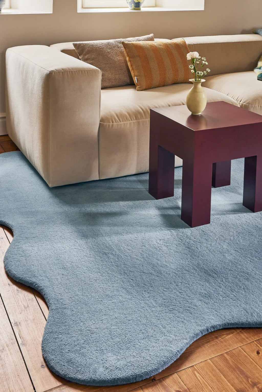 Layered Scallop Wool Rug, a plush light blue wool area rug with a unique wavy, scalloped edge design, enhancing a modern living room's aesthetic. Perfect for adding soft texture and contemporary st...
