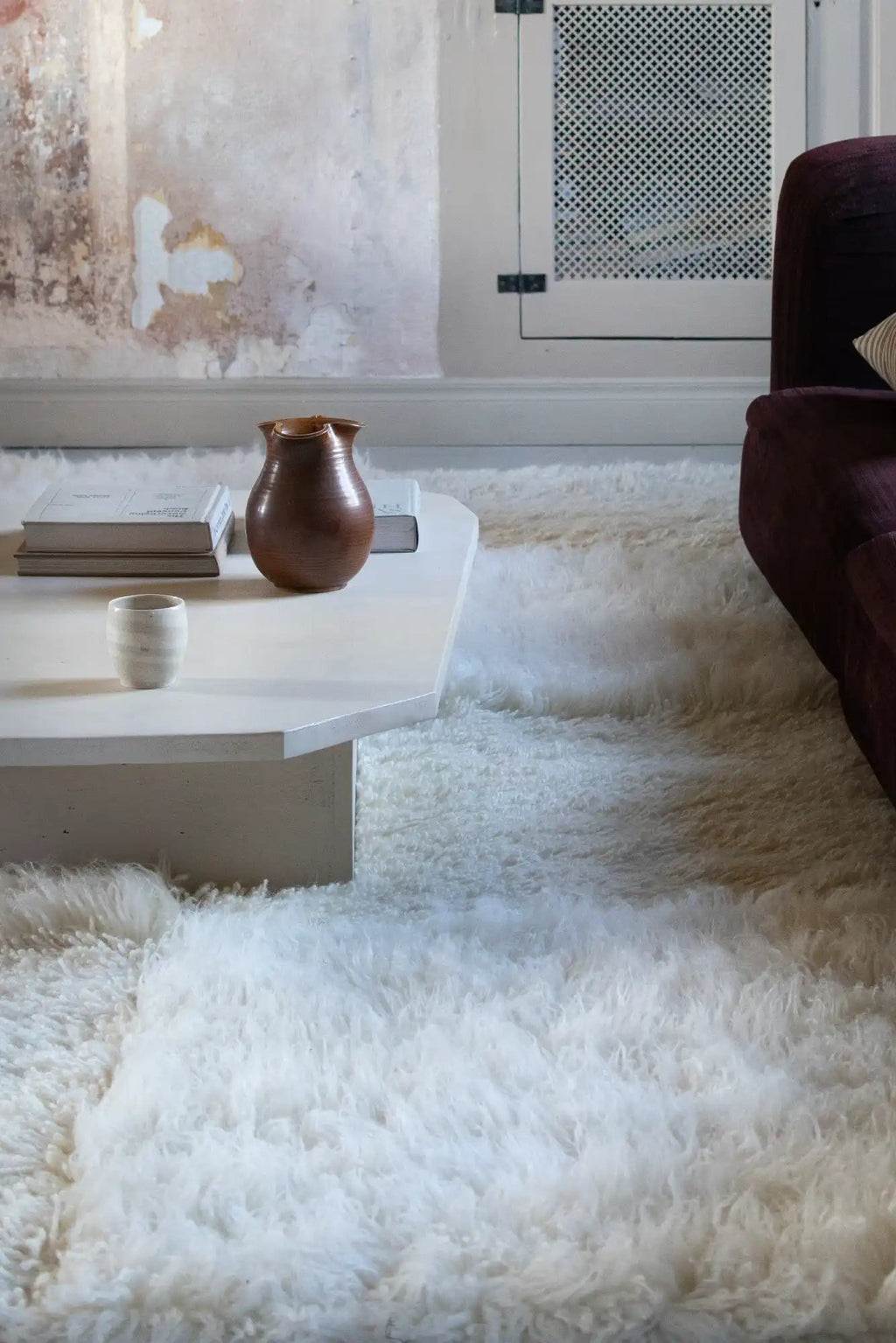 Layered Shaggy Checked Rug, a luxurious white sheepskin-like area rug with a deep pile and soft texture, covering a rustic room floor. Perfect for adding warmth and comfort to living spaces.