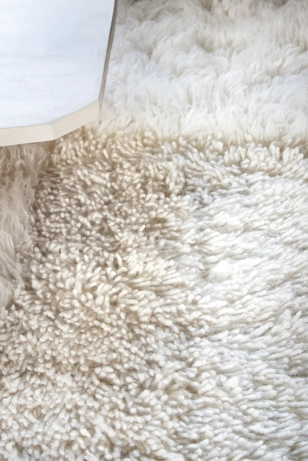 Layered Shaggy Checked Rug, a luxurious off-white wool rug featuring a deep pile and textured shaggy weave, partially obscured by a white furniture corner. Perfect for adding warmth and comfort to...