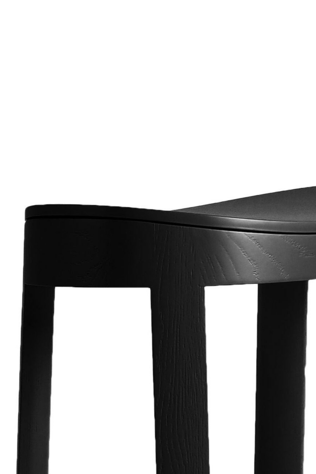 Made by Choice Lammi Bar Stool, a modern minimalist bar stool crafted from solid wood with a matte black finish and visible wood grain texture. It features a subtly curved ergonomic seat and clean, straight legs, embodying Scandinavian design principles. Perfect as stylish kitchen island seating or for a contemporary home bar area.