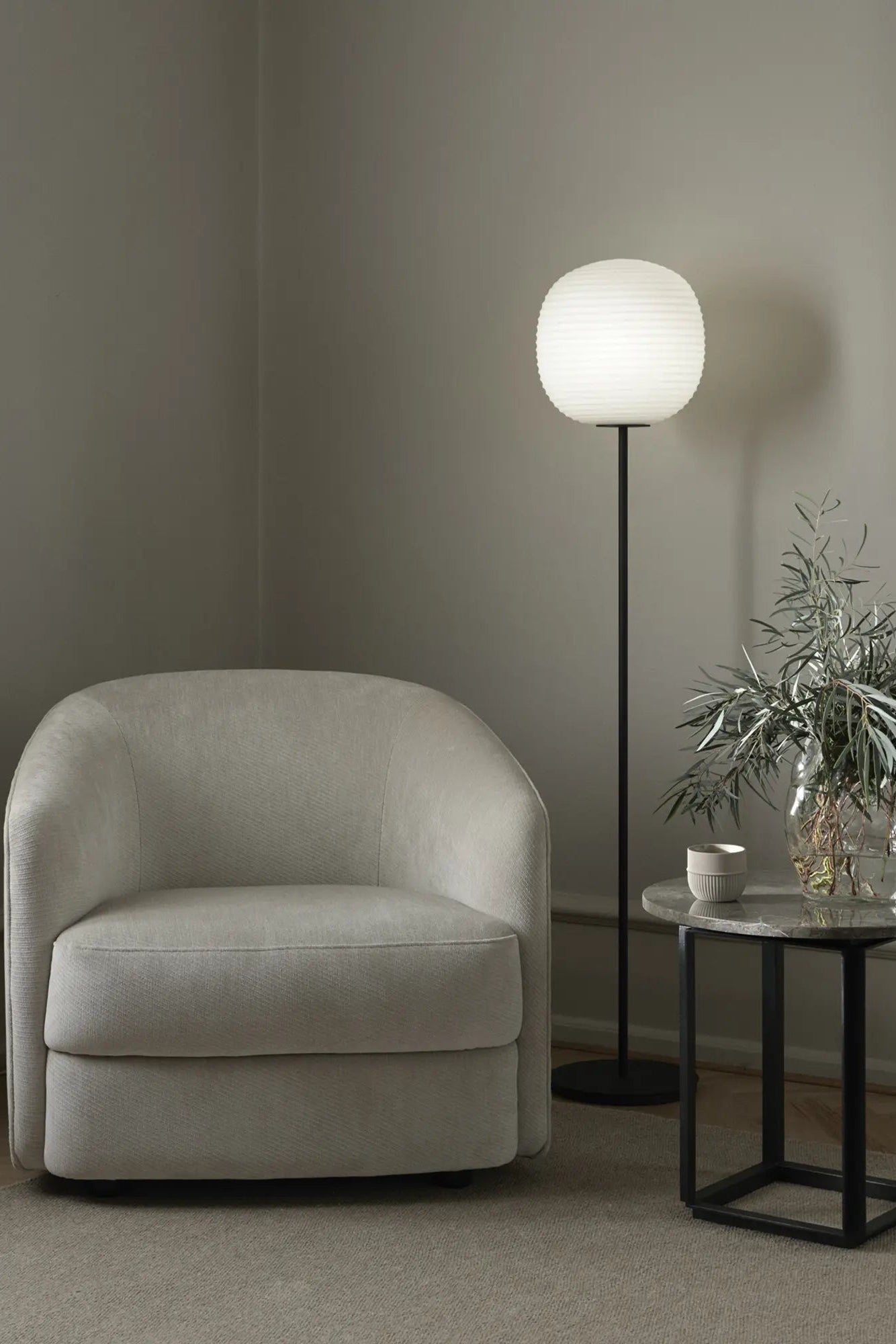 Unique lantern floor lamp casting a warm glow in a contemporary bedroom