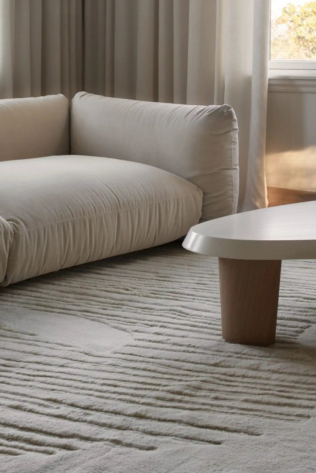 Layered Artisan Guild Wool Rug, a light cream-colored hand-tufted wool rug with a unique wavy, textured pattern. Perfect for adding warmth and sophisticated design to any modern living room.