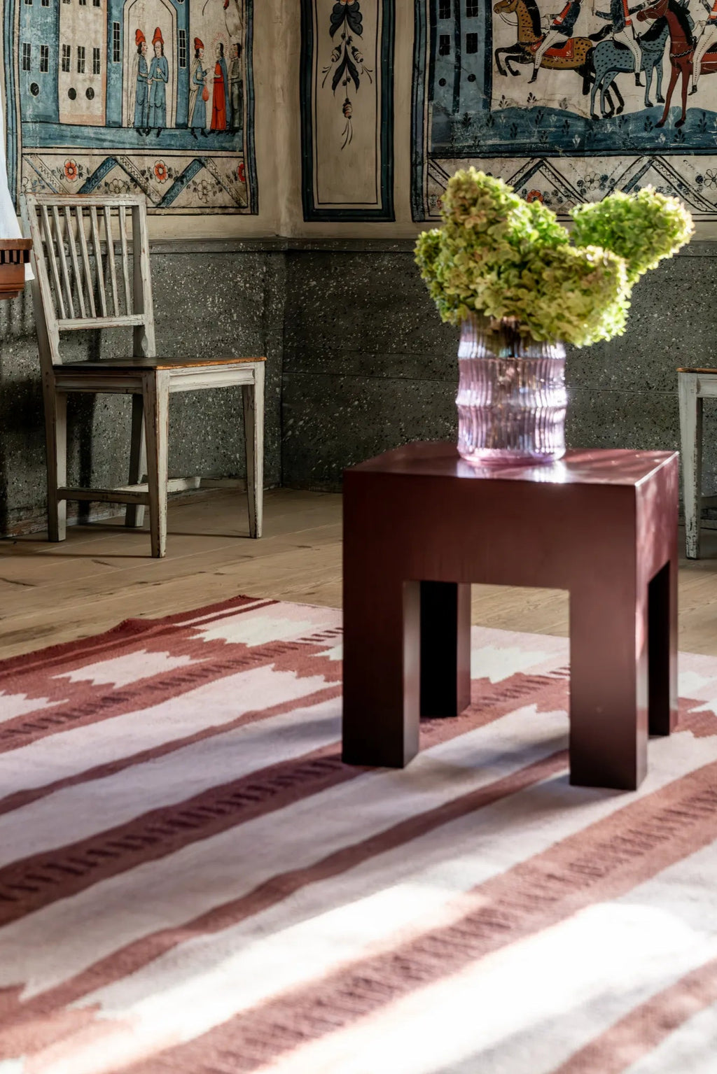 Layered Iris Wool Rug - Raspberry, a premium hand-knotted wool rug featuring an ikat-inspired pattern in soft raspberry and cream hues. This stylish area rug adds warmth and texture to any living s...