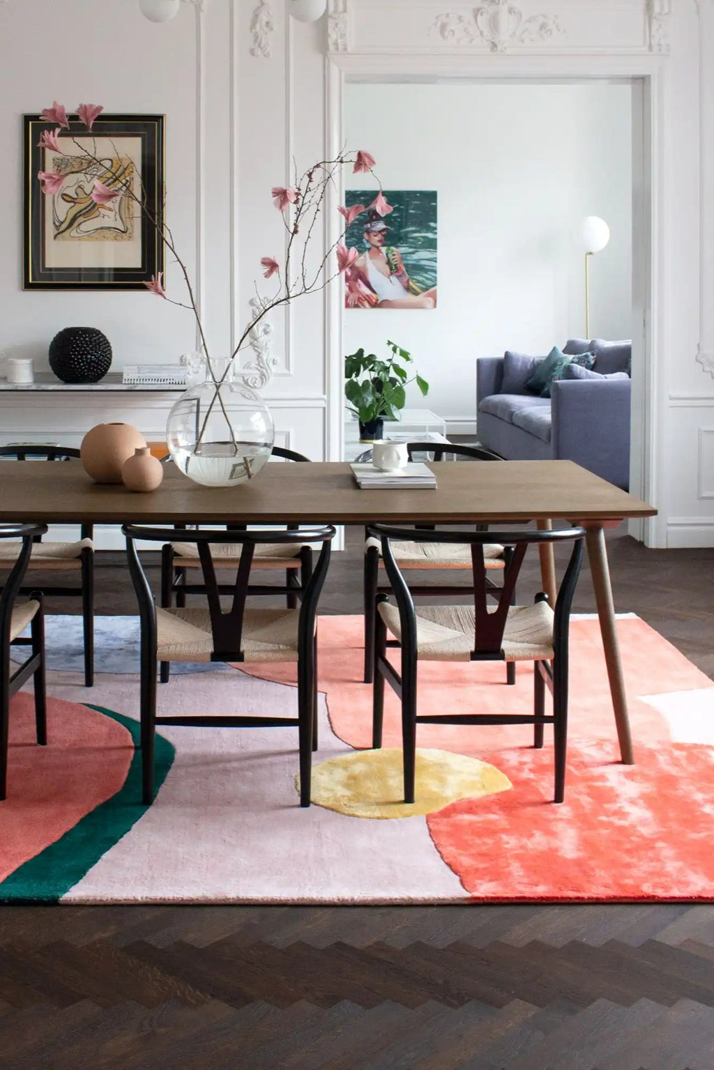 Layered Flower Field Wool Rug, a vibrant abstract rug featuring organic shapes in pink, coral, yellow, and green on a light pink background. This modern area rug adds a playful touch to any contemp...