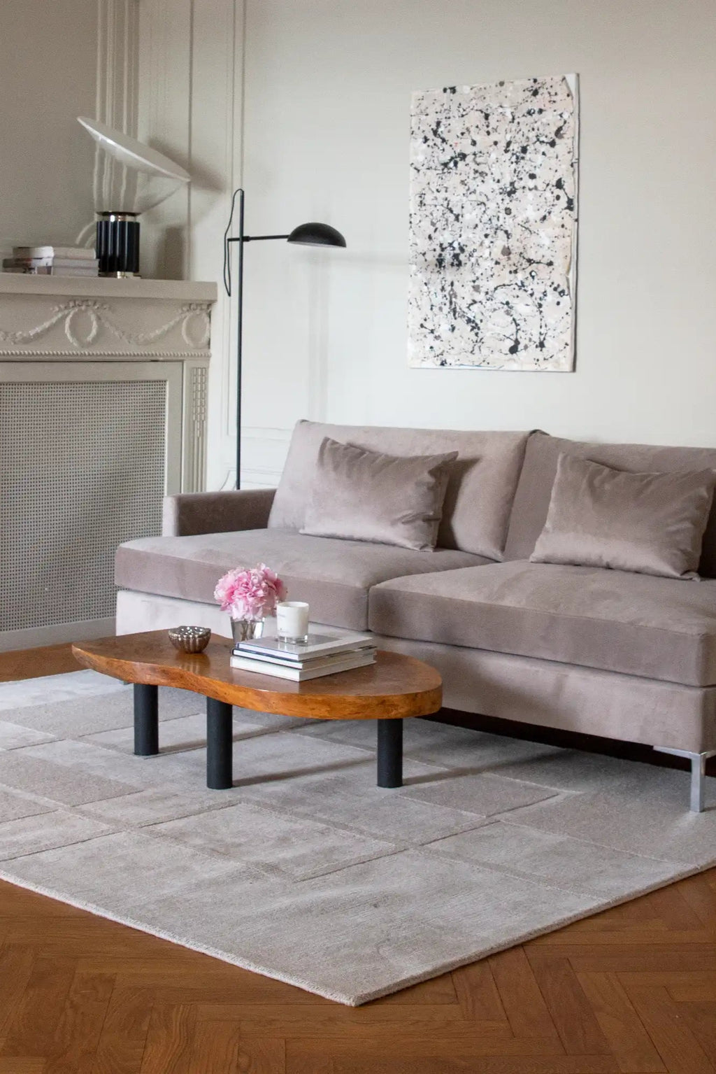Layered Swedish Grace Wool Rug, a light gray rectangular area rug with subtle geometric block patterns, placed on a warm hardwood floor in a living room. Perfect for adding soft texture and modern...