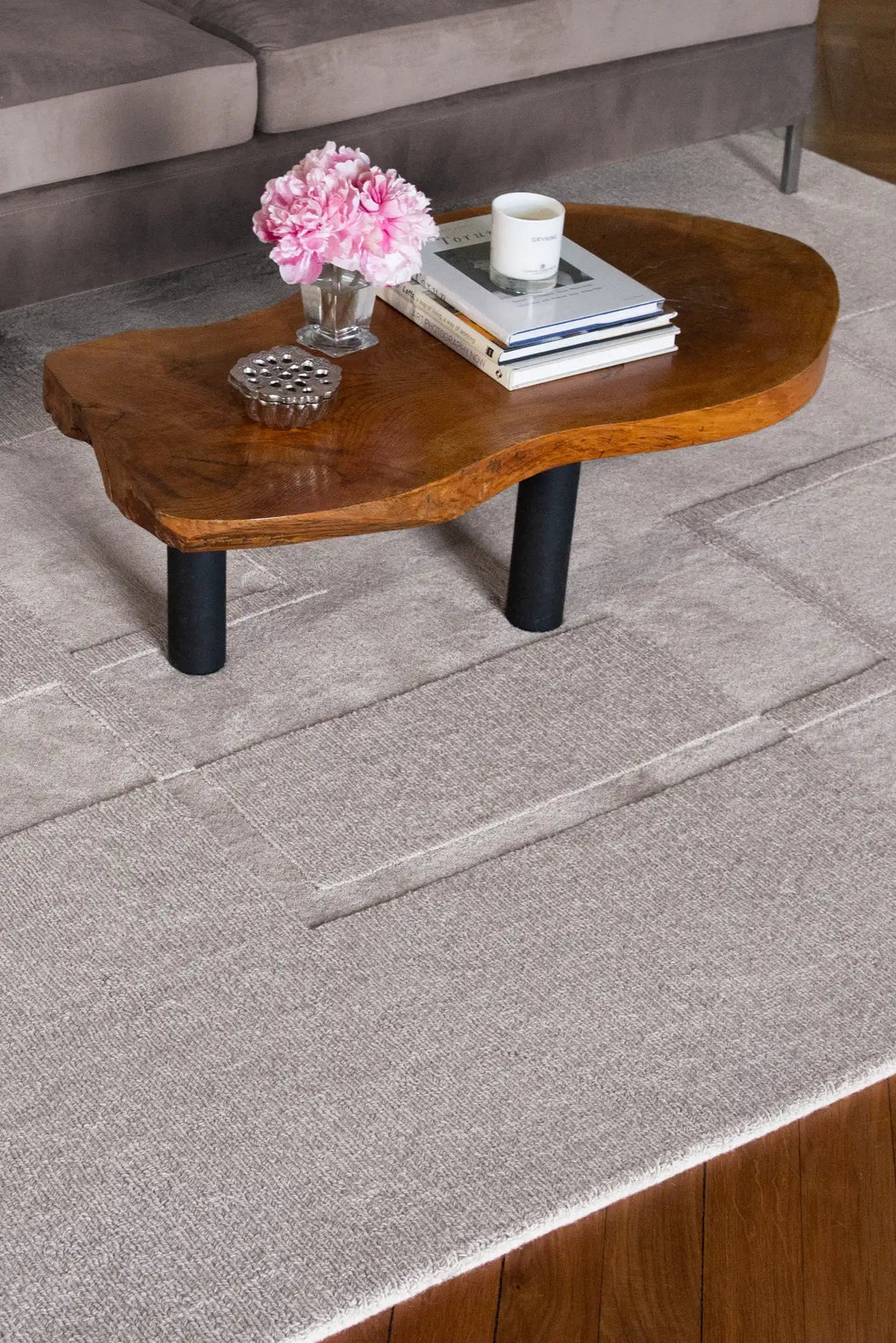 Layered Swedish Grace Wool Rug, a light grey textured wool area rug with subtle geometric patterns, complementing a modern living room setting. Perfect for adding warmth and sophisticated style to...