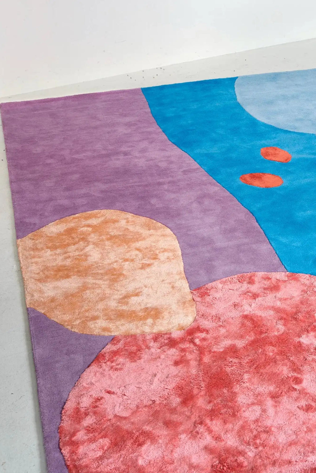 Layered Secret Garden Wool Rug, a vibrant abstract area rug featuring a playful design with blocks of purple, blue, light blue, peach, and coral pink. Perfect for adding a colorful, modern touch to...