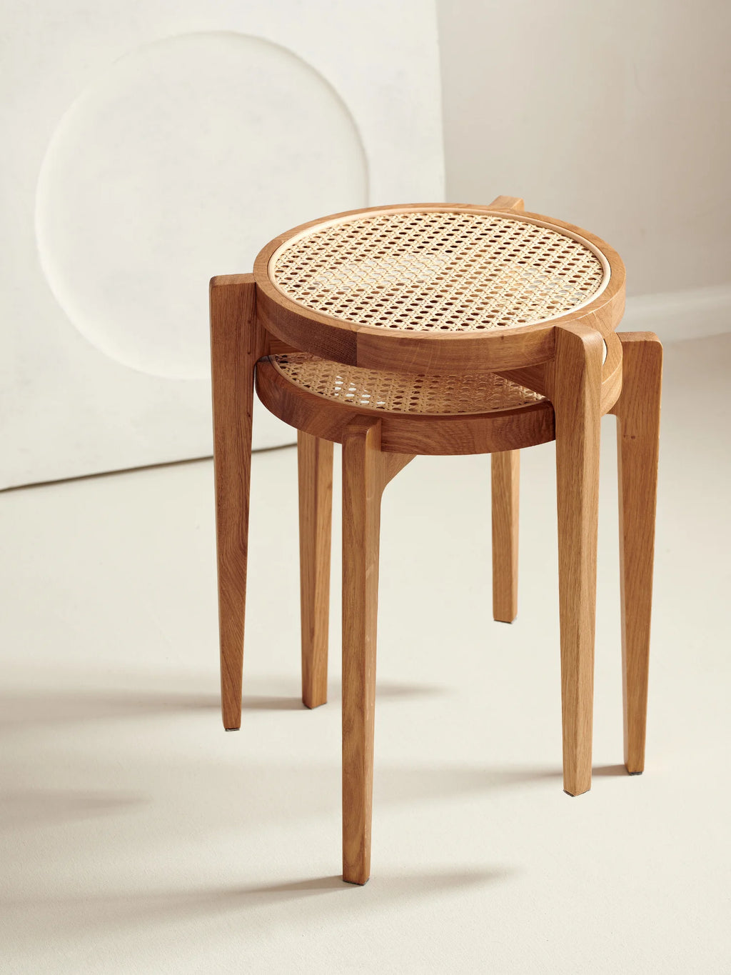 NORR11 Le Roi Side Table, a nesting set of two round light-brown oak wood tables featuring natural rattan cane tops, showcased on a light studio background. Premium craftsmanship for elegant living.