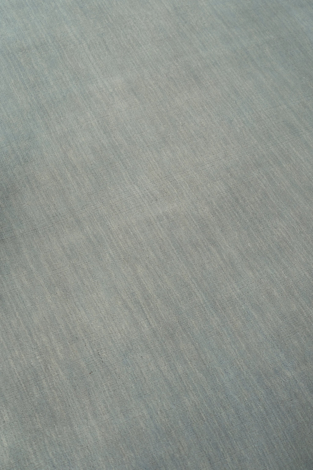 Linie Design Abyss Bliss Wool Rug, a premium hand-knotted wool area rug featuring a subtle mélange of muted blue-grey and soft cream tones, creating a richly textured surface with organic color.