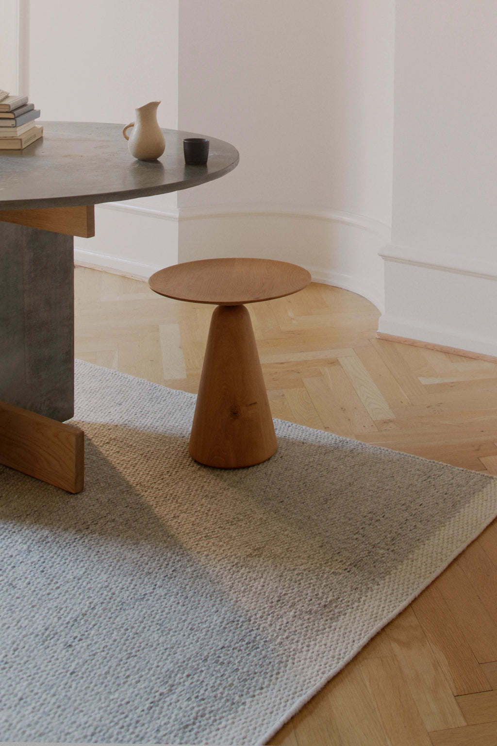 Linie Design Frode Wool Rug, a hand-woven wool area rug featuring a subtle heathered light grey and oatmeal textured weave with a distinct lighter cream border. This Scandinavian-inspired rug offers a minimalist and organic modern aesthetic, ideal for adding cozy warmth and a natural feel to contemporary living rooms, bedrooms, or Japandi interiors.