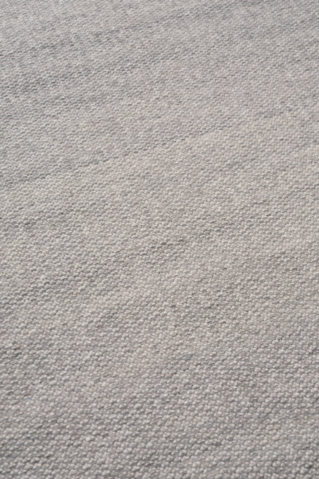 Linie Design Frode Wool Rug, a premium hand-knotted wool area rug in soft light grey and off-white tones, featuring a plush, textured weave with subtle natural variations. This Scandinavian-inspired natural fiber rug is ideal for adding cozy warmth to minimalist living rooms, modern bedrooms, or japandi interiors.
