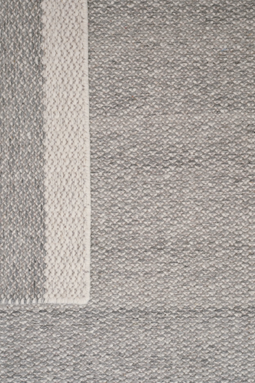 Linie Design Frode Wool Rug, a premium hand-woven wool area rug featuring a dense, chunky textured flatweave in a mélange of natural grey and off-white tones. It includes a distinct vertical stripe pattern on the left side, adding subtle visual interest with its varying weave and lighter shades. This Scandinavian-inspired rug is perfect for adding cozy warmth and organic modern style to living rooms, bedrooms, or minimalist interiors.