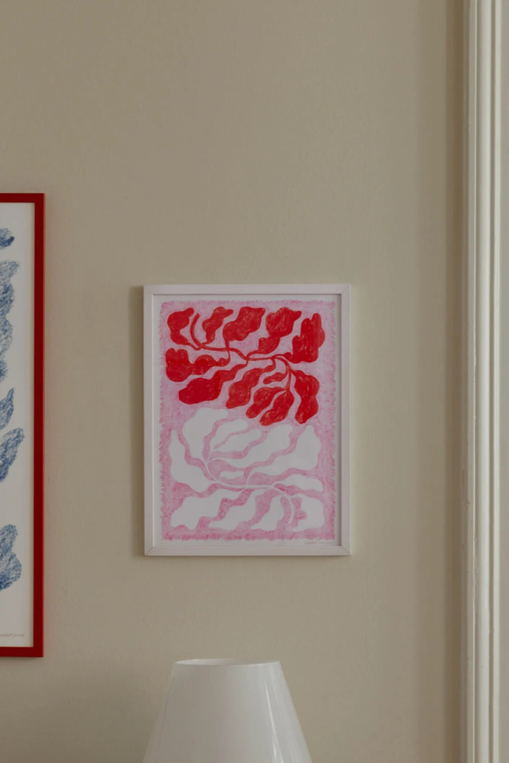 The Poster Club Longing, a vibrant abstract art print featuring organic, flowing shapes in bold red and soft pink tones with a hand-drawn texture, set against a crisp white background, presented in a clean white frame. Ideal as contemporary wall art for a modern living room, bedroom, or a playful addition to a gallery wall.