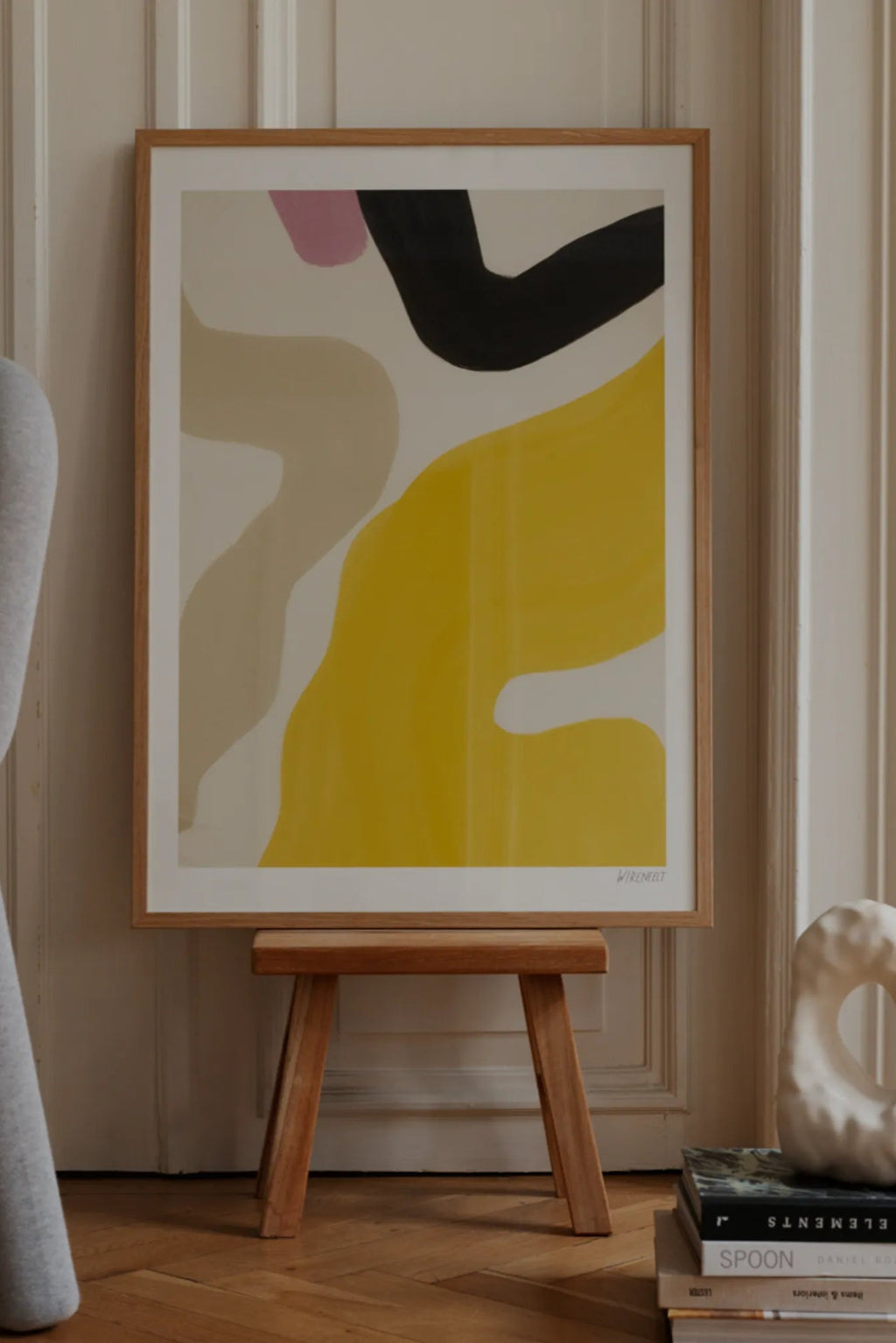 The Poster Club Solero, an abstract art print featuring bold organic shapes in bright yellow, warm beige, deep black, and soft pink against a creamy off-white background, presented in a natural oak frame with a crisp white mat. This contemporary wall art is ideal for creating a vibrant focal point in modern living rooms, bedrooms, or gallery walls.