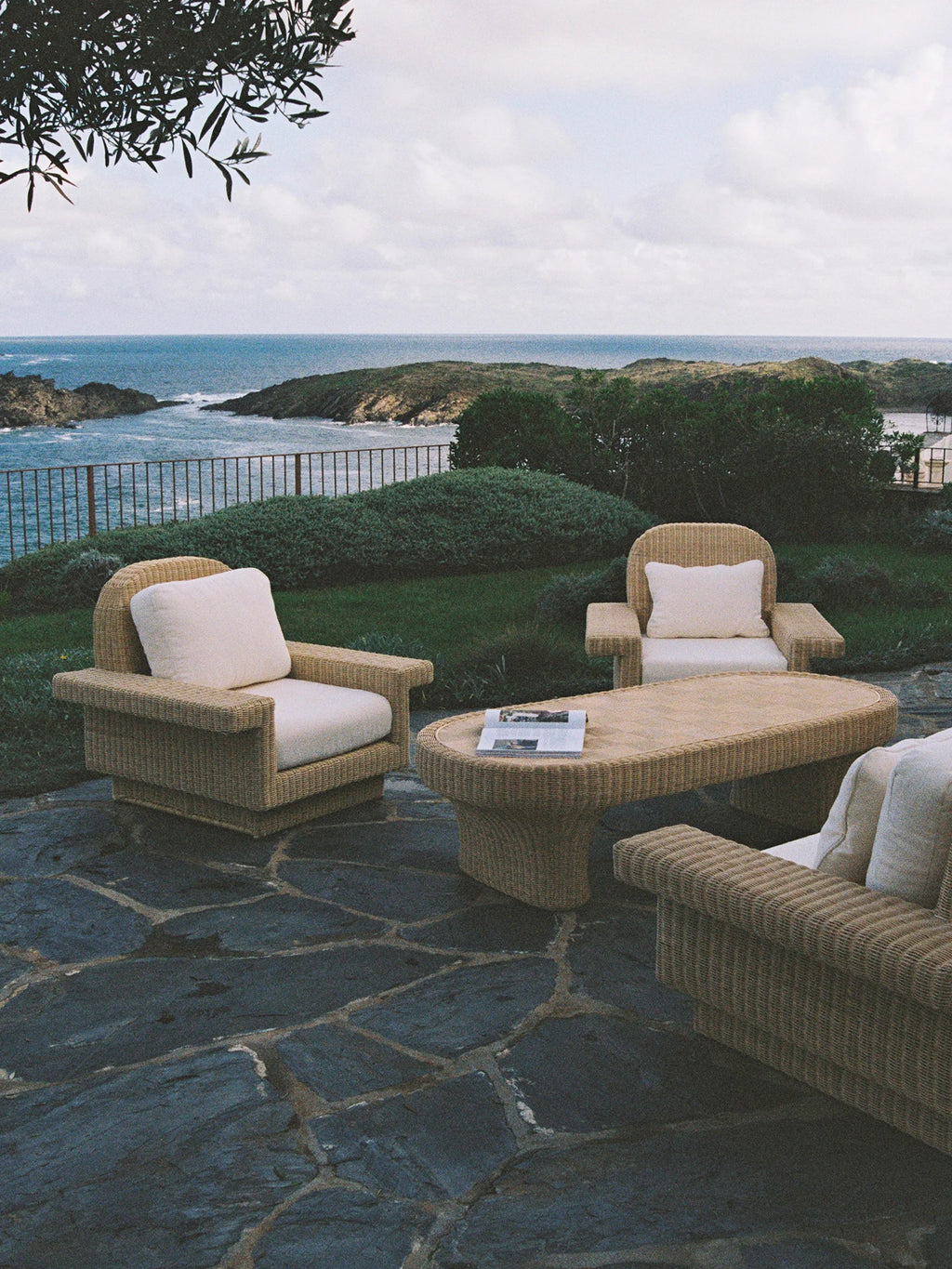 Heaps & Woods Lola Lounge Chair w/ Armrest, a robust natural woven rattan lounge chair featuring a substantial block-like frame, wide flat armrests, and plush cream-colored cushions.