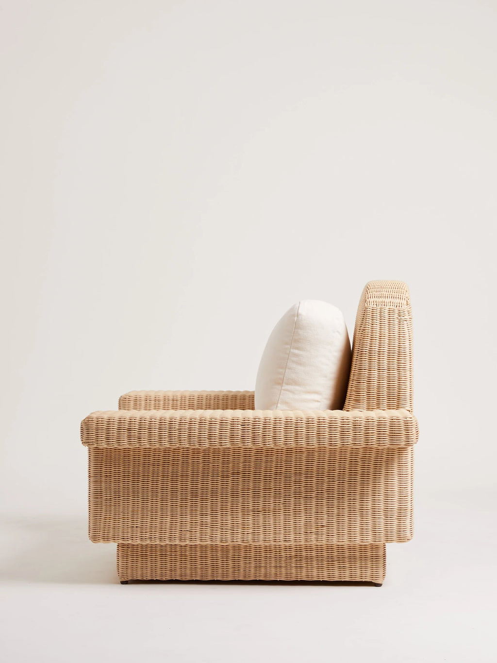 Heaps & Woods Lola Lounge Chair w/ Armrest, a natural woven rattan lounge chair featuring a distinctive structured silhouette with chunky armrests and a low profile, crafted from light beige rattan with a cream-colored back cushion. This organic modern accent chair is perfect for coastal living rooms, sunrooms, or contemporary bedroom styling.
