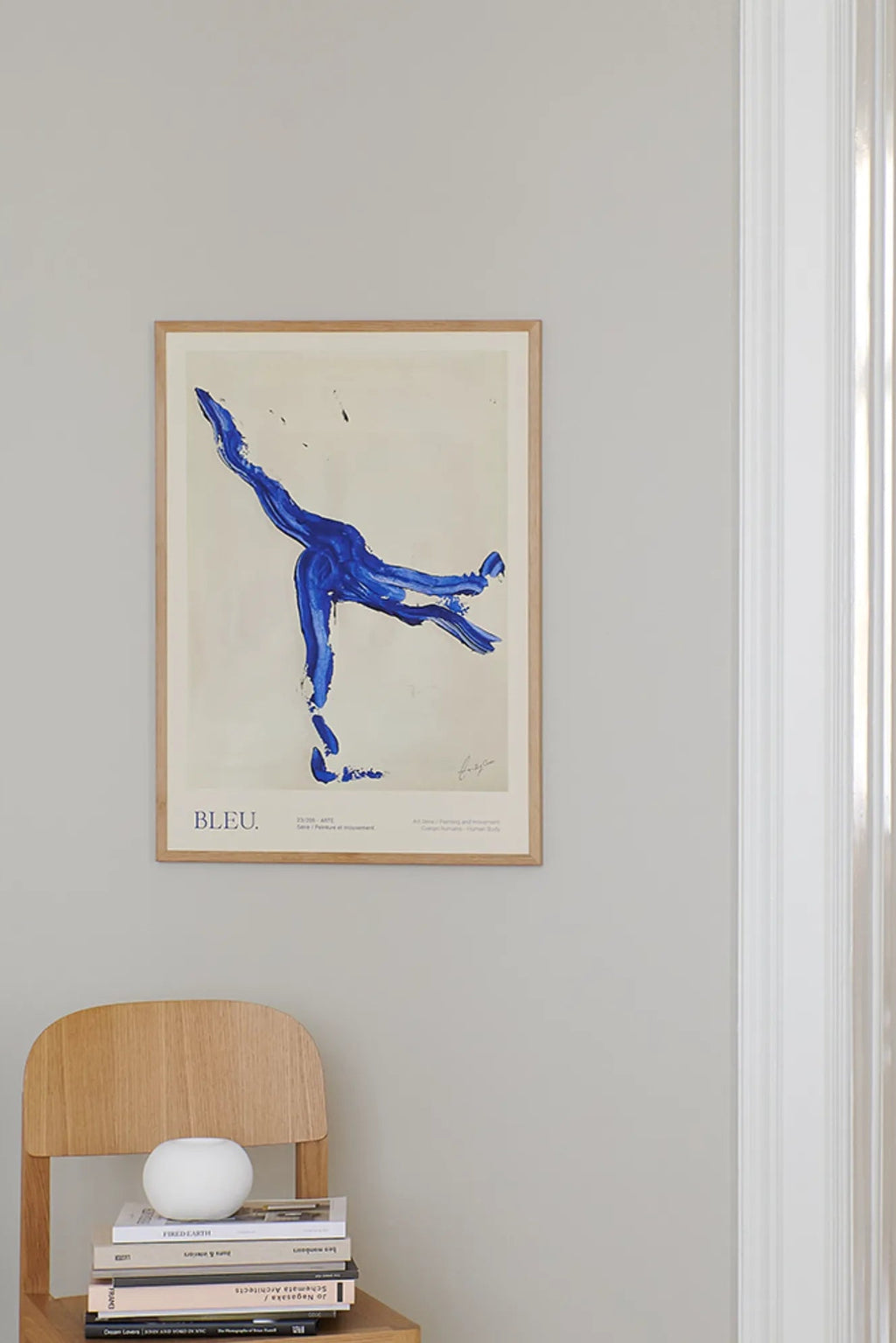 The Poster Club Bleu, a modern abstract art print featuring vibrant royal blue brushstrokes creating an expressive human form or figure in motion against a light beige background. This contemporary art print is presented in a natural oak frame with a clean white mat. Perfect for minimalist gallery walls or as a statement piece in modern living rooms and bedrooms.