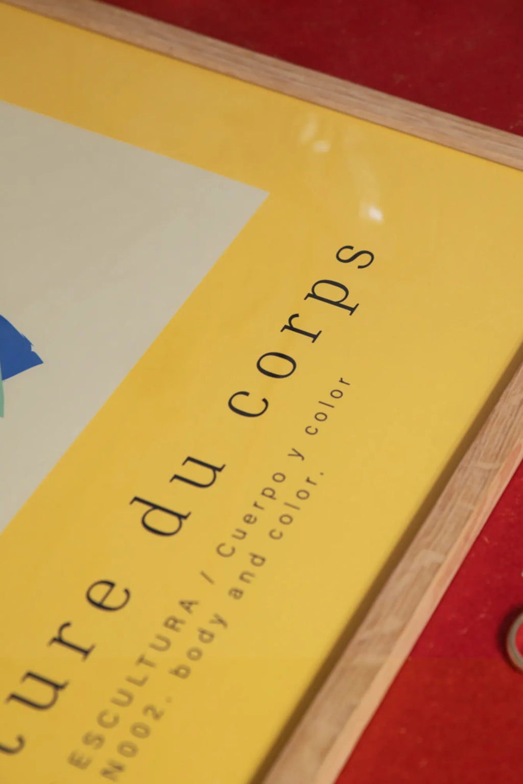 The Poster Club Corps Series, a modern abstract art print featuring a vibrant yellow background with an off-white section, black minimalist typography reading "Corps du corps" and "N002. body and color", accented by subtle blue and green abstract shapes, housed in a natural oak frame. This graphic wall art is perfect for contemporary gallery walls, Scandinavian living rooms, or a stylish home office.