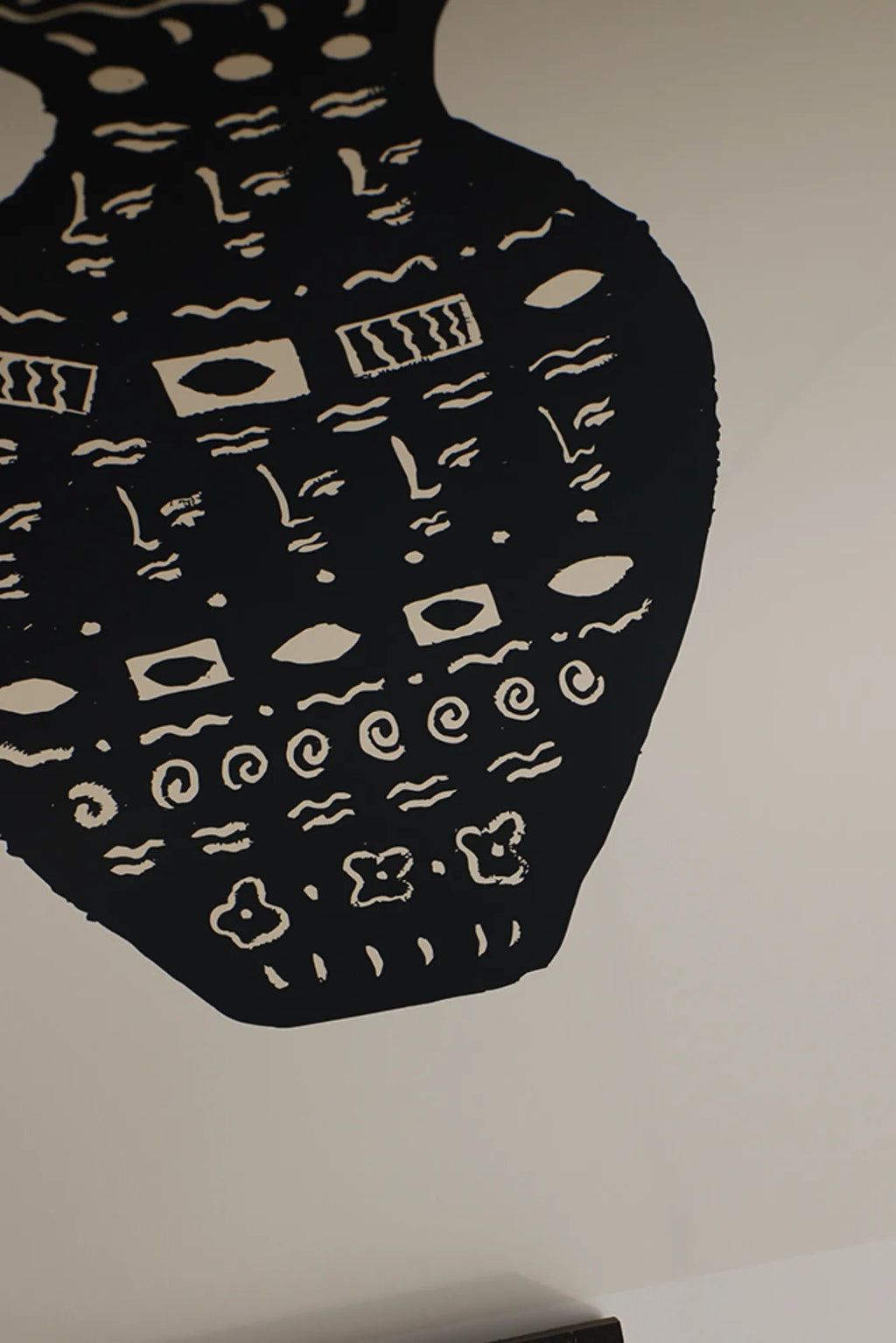 The Poster Club Les Objets, an abstract art print featuring a large organic black silhouette filled with repeated light beige primitive motifs, including stylized faces, eyes, wavy lines, and spirals, against a crisp off-white background. This graphic minimalist poster is perfect for contemporary gallery walls, modern minimalist interiors, or Scandinavian-inspired living rooms.