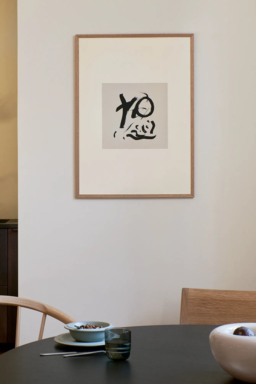 The Poster Club Sense, a modern minimalist abstract art print featuring bold black brushstrokes on a light grey background, presented in a natural oak frame with a crisp white mat. This contemporary framed poster is perfect for Scandinavian living rooms, Japandi dining areas, or minimalist gallery walls.