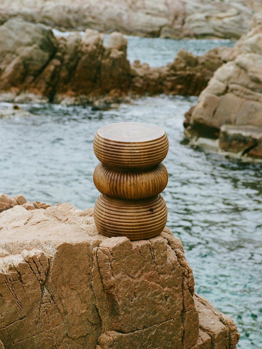 Heaps & Woods Luka Stool, a sculptural organic modern accent stool crafted from warm natural solid wood with a unique stacked, rounded cylindrical shape. Each segment features a distinctive horizontally ribbed or fluted texture, enhancing its natural wood grain and rustic appeal. This versatile piece functions beautifully as a decorative side table, bedside table, or extra seating for living rooms, bedrooms, or coastal-inspired interiors.