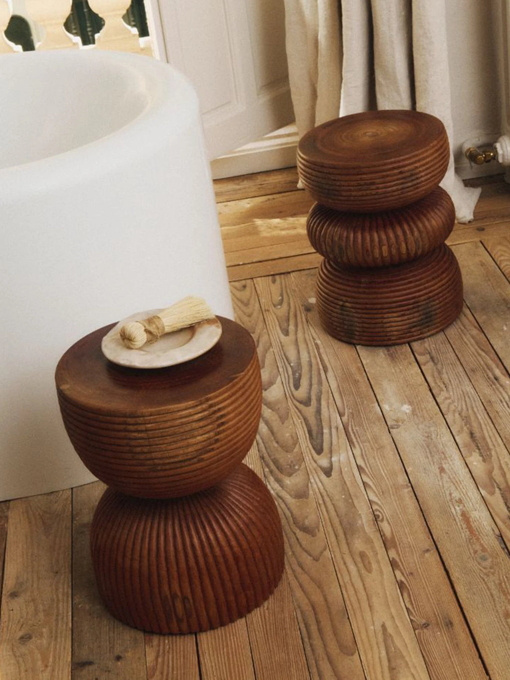 Heaps & Woods Luka Stool, a sculptural organic modern stool crafted from rich reddish-brown solid wood, featuring stacked, rounded forms with deeply grooved, turned wood textures creating a distinct, handcrafted silhouette. Ideal as a unique side table, accent stool, or bedside table in natural modern, rustic, or wabi-sabi inspired living spaces and bathrooms.