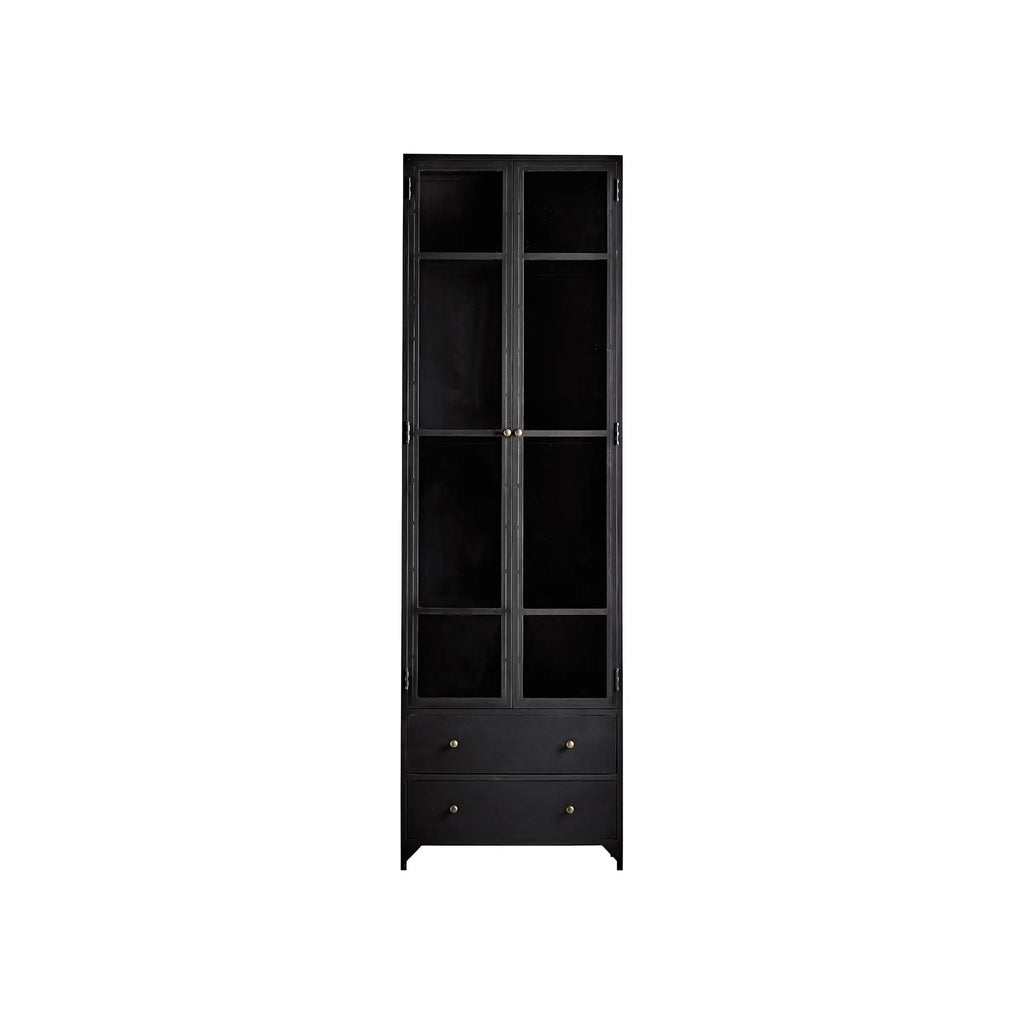 Tine K Metal High Cabinet, a sleek industrial chic display cabinet crafted from matte black metal with clear glass paneled doors and elegant brass knob handles. This tall, narrow vitrine features two upper glass sections for display and two lower drawers for concealed storage. Ideal for minimalist living rooms, dining rooms, or home offices seeking modern storage solutions.