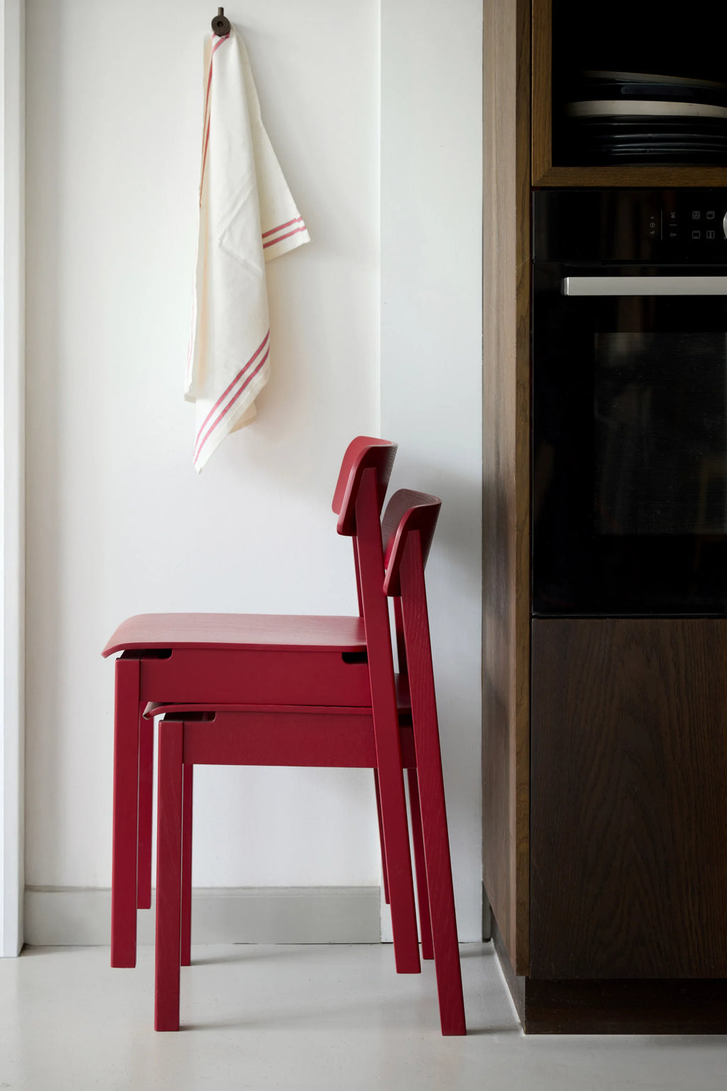 MOEBE Everyday Chair, a vibrant red solid wood chair with a modern minimalist design and a smooth matte finish that highlights the natural wood grain. This stackable Scandinavian dining chair features a gently curved backrest and clean, straight legs, offering both style and practicality. Ideal as a contemporary kitchen chair, a compact dining room chair, or a versatile accent chair for modern homes and small spaces.