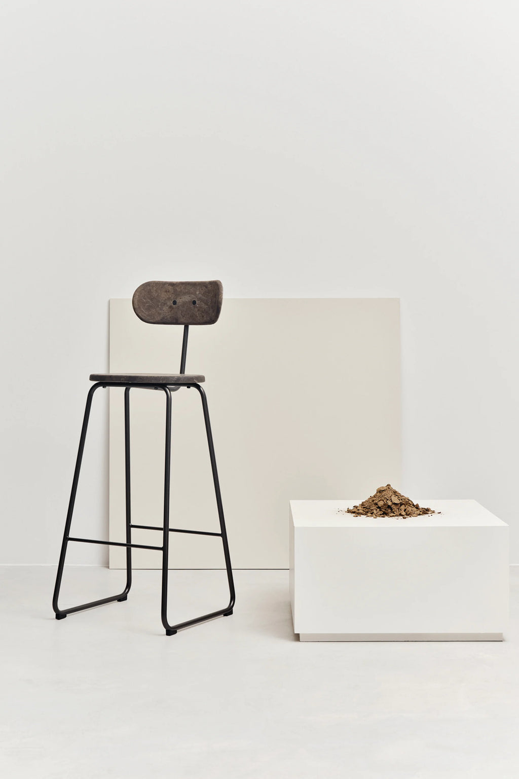 Mater Earth Counter Chair, a modern, eco-conscious design with a dark brown recycled composite seat and backrest, supported by a sleek black metal frame, presented on a pristine white background.