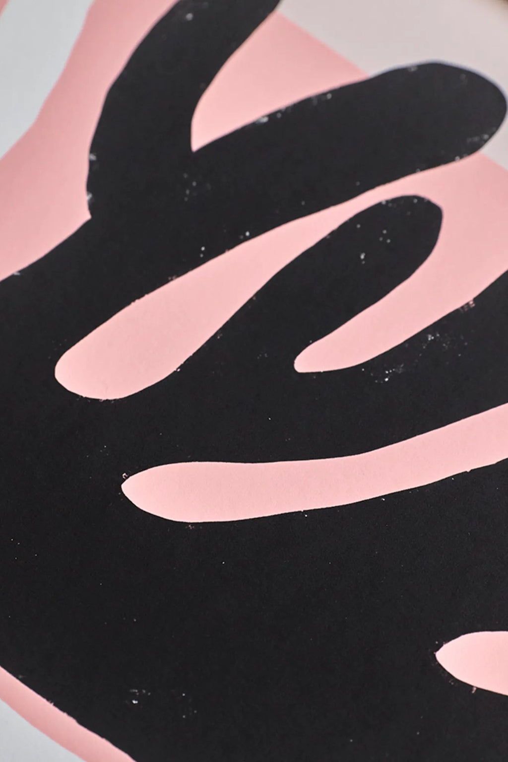 The Poster Club Black And White Corals, an abstract art print featuring bold black organic shapes reminiscent of modern coral forms, set against a soft, pale pink background with a subtle textured finish.