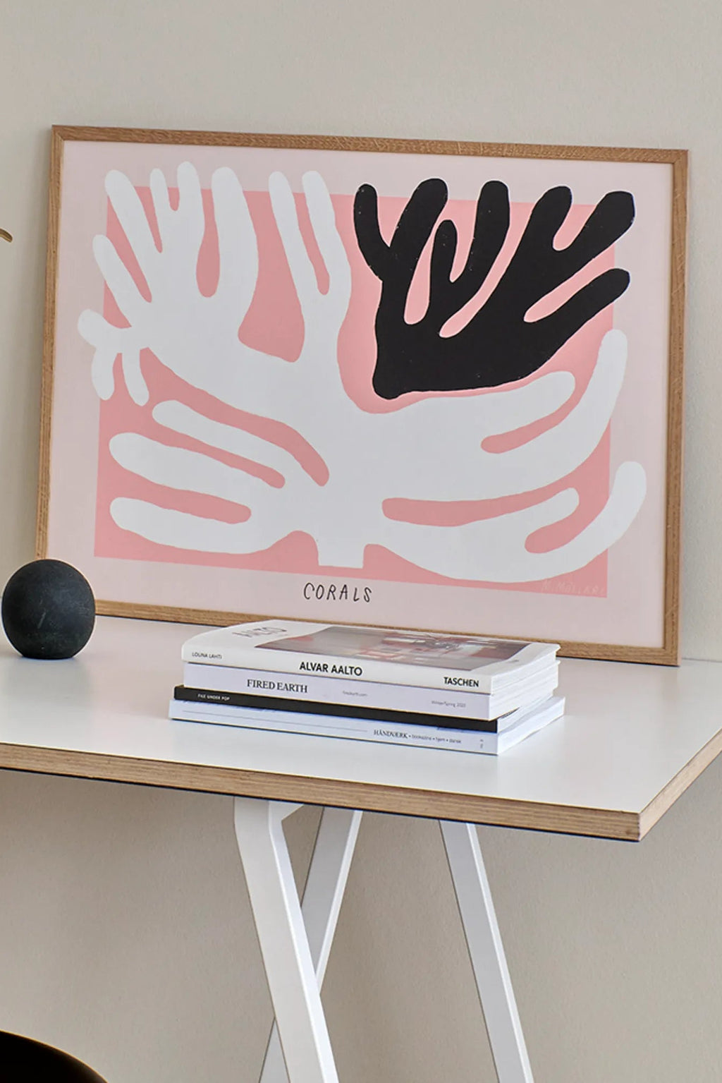 The Poster Club Black And White Corals, an abstract art print featuring bold, organic black and white coral shapes against a soft pastel pink background, presented in a minimalist natural oak frame. This contemporary poster adds a touch of organic modern style to Scandinavian living rooms, coastal bedrooms, or curated gallery walls.