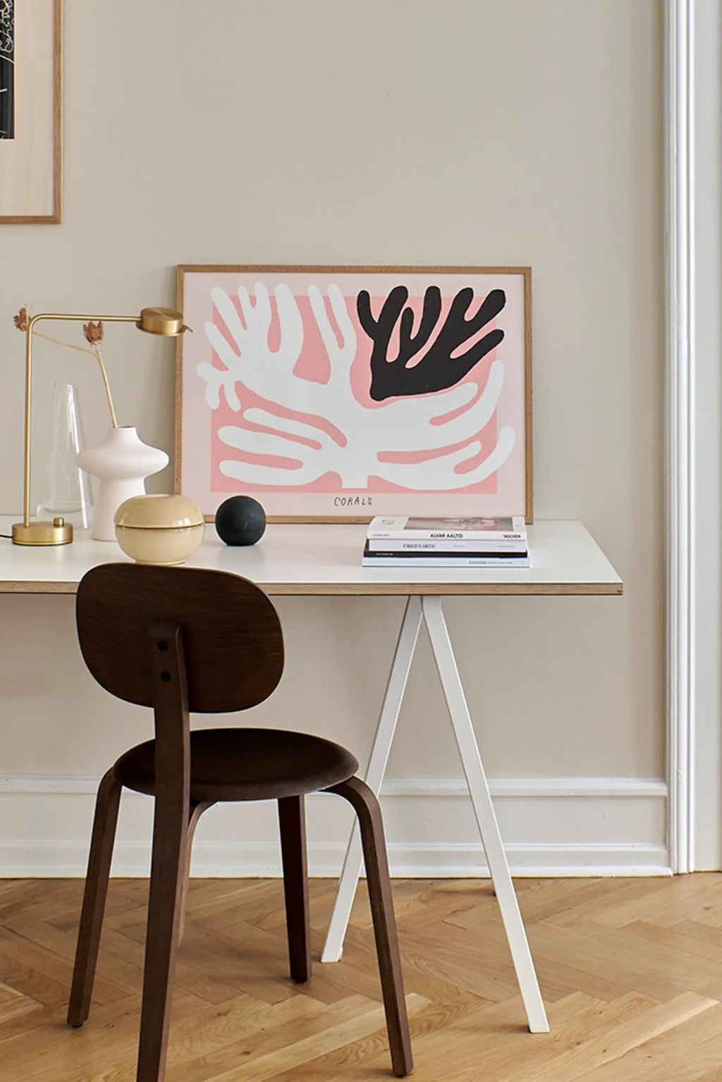 The Poster Club Black And White Corals, an abstract art print featuring organic coral shapes in bold white and black against a soft blush pink background, framed in a light natural oak frame. This contemporary minimalist poster offers a modern aesthetic for gallery walls, home office decor, or Scandinavian living rooms.